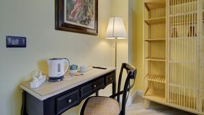 Una habitación con un escritorio, una silla, una lámpara, un cuadro enmarco y un armario de madera.