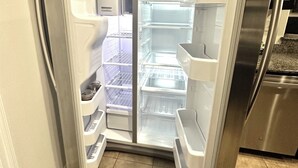 Une cuisine moderne équipée d’un réfrigérateur encastré en acier inoxydable, d’un four à micro-ondes et d’une cuisinière.