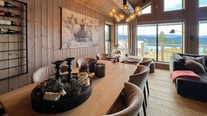 En matplats med ett långt träbord, stolar och en kristallkrona. Till vänster finns ett vinställ och på väggen hänger en tavla.