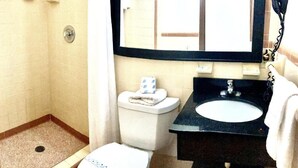 A bathroom with a shower, toilet, sink, and mirror. - Budget inn (Okeechobee)