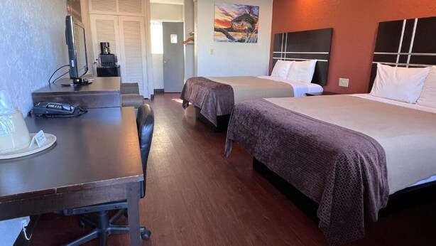 A hotel room with two beds, a desk with a computer, and a coffee machine. - Budget inn (Okeechobee)
