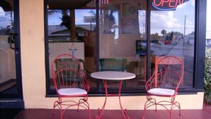 A storefront with a glass door, two red metal chairs, and a small round table. - Budget inn (Okeechobee)