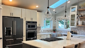 A modern kitchen with a central island, stainless steel appliances, and pendant lighting.