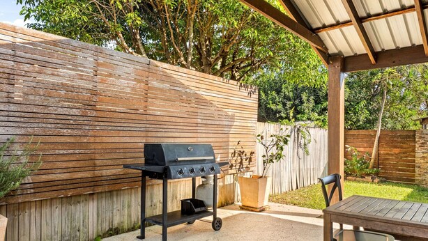 An outdoor patio with a grill, a table, and chairs. - 2-bed Beach Escape With Courtyard (Gold Coast)