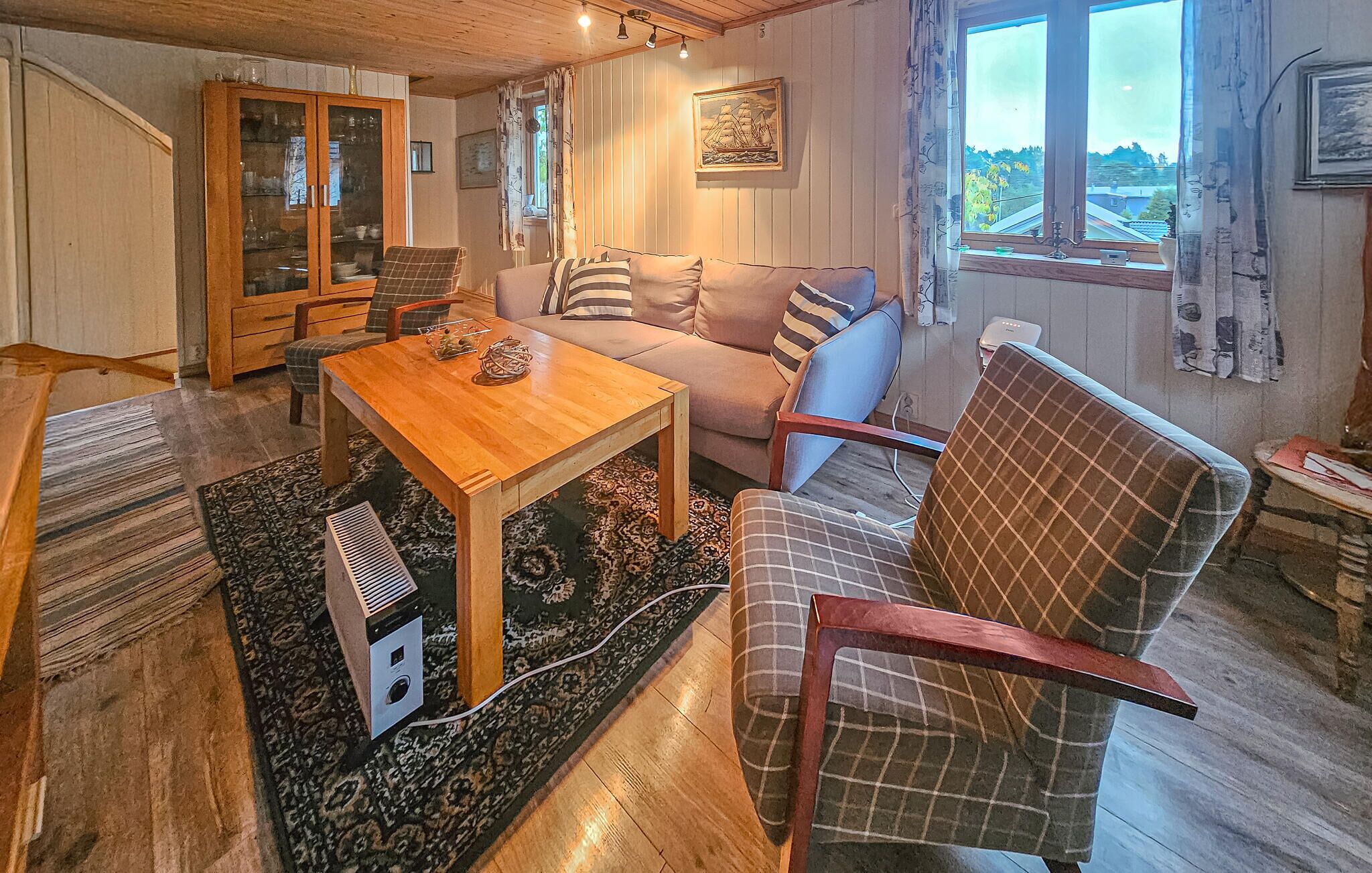 A cozy living room with a wooden table, a sofa, and a plaid armchair.