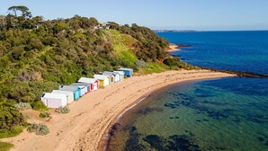 A coastal area with a row of beach huts along the shoreline. - Villa Capri | Luxe Modern by the Village (Mount Eliza)