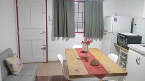 A compact kitchen with a wooden table, a refrigerator, and a microwave. - Don Alegre Enjoy the simplicity of this quiet and central lodging. (Corrientes)