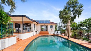 A modern house with a swimming pool, solar panels, and outdoor furniture. - Peaceful Family Home: 4-bed, Pool, Alfresco Dining (Brisbane)