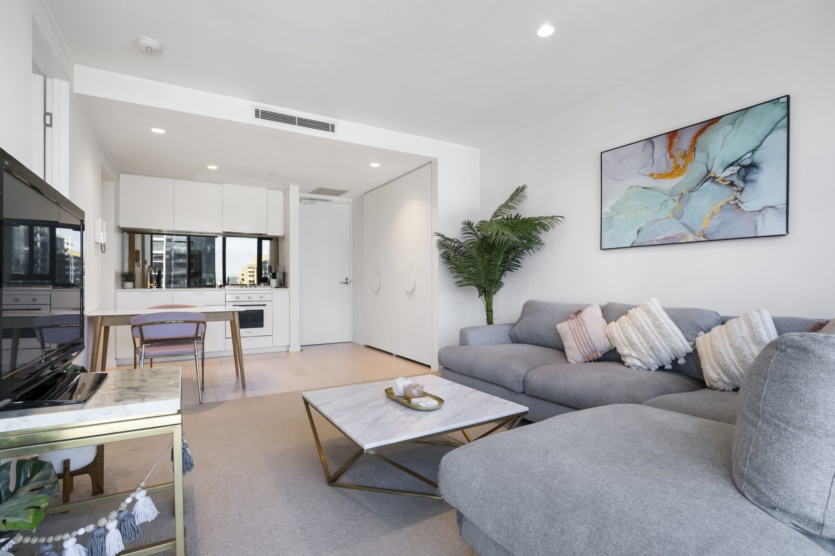 A modern living room with a grey sofa, a coffee table, and a dining area with a chair and table.