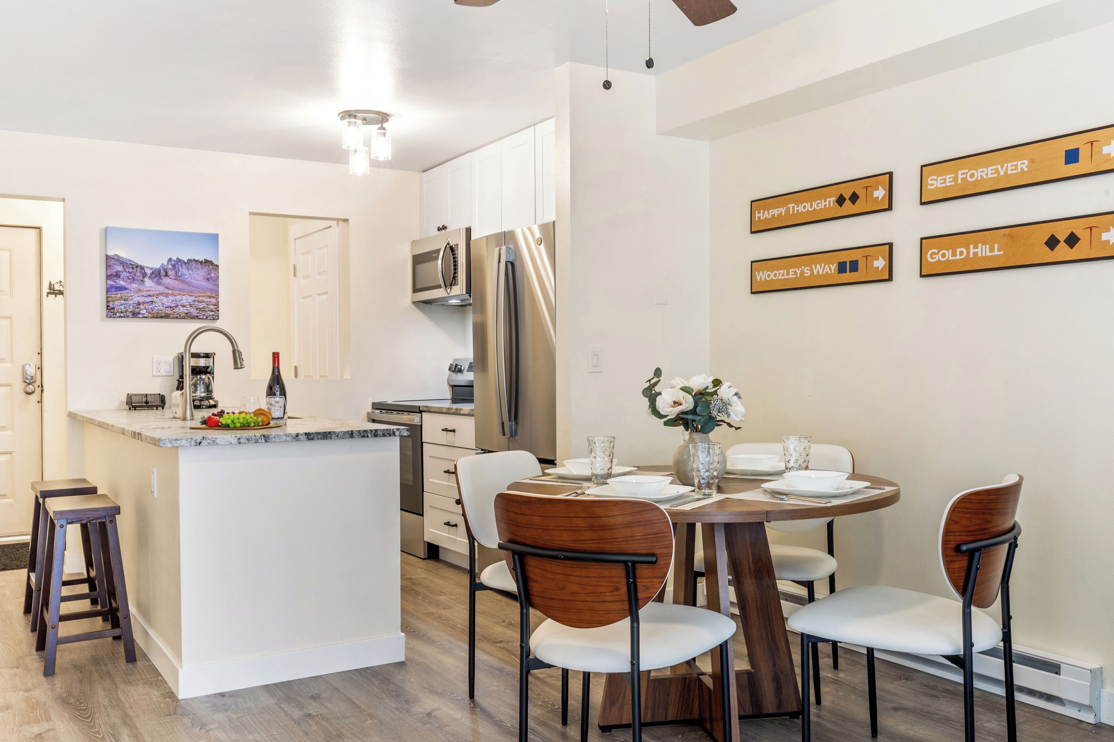 A modern kitchen with a central island, dining table, and chairs. There are cabinets, a refrigerator, and a microwave.