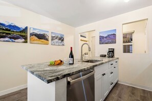 Cocina con encimeras de granito, electrodomésticos de acero inoxidable y pinturas de paisajes montañosos.