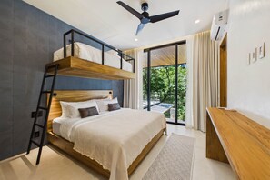 A modern bedroom with a bunk bed, a desk, and a large window with a view of greenery.
