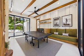 Een modern interieur met een tafeltennistafel, een groene bank en ingelijste foto’s aan de muur.
