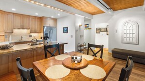 A modern kitchen with wooden cabinets, a central island, and a dining area with a wooden table and chairs. - Charming 2BR, 2BA condo in the heart of Telluride, perfect for 6 guests. (Telluride)