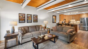 A modern living room with two sofas, a coffee table, and a kitchen area with wooden cabinets and stainless steel appliances. - Charming 2BR, 2BA condo in the heart of Telluride, perfect for 6 guests. (Telluride)
