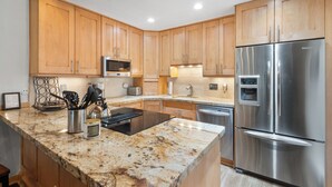 A modern kitchen with wooden cabinets, stainless steel appliances, granite countertops, and recessed lighting. - Charming 2BR, 2BA condo in the heart of Telluride, perfect for 6 guests. (Telluride)