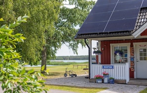 Un espace d’accueil avec un panneau indicateur, un petit coin salon extérieur et un panneau solaire sur le toit.