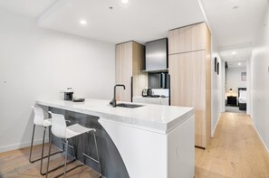 Cocina moderna con una isla central, taburetes blancos y armarios de madera.