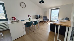 A modern living room with a dining area, a television, and a large window with a view. - Apartment on the Sentiero Valtellina bike path, just minutes from Lake Como (Morbegno)