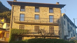 A multi-story stone building with balconies, a stone wall entrance, and a clear sky. - Apartment on the Sentiero Valtellina bike path, just minutes from Lake Como (Morbegno)