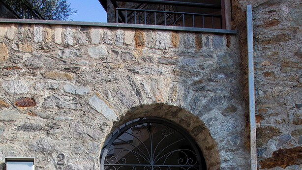 A stone building with a metal gate, a mailbox, and a utility box. - Apartment on the Sentiero Valtellina bike path, just minutes from Lake Como (Morbegno)