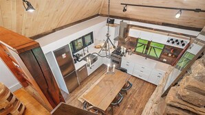 Une cuisine moderne avec une table et des chaises en bois, un lustre et une vue sur l’extérieur.