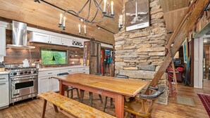 Une cuisine rustique avec un mur en pierre, un plafond en bois et un lustre.