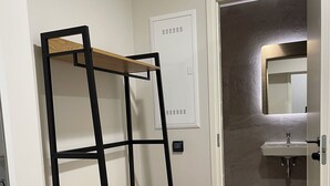 Een kamer met een stapelbed, een badkamer met een wastafel en spiegel, en een deur die leidt naar een andere kamer.