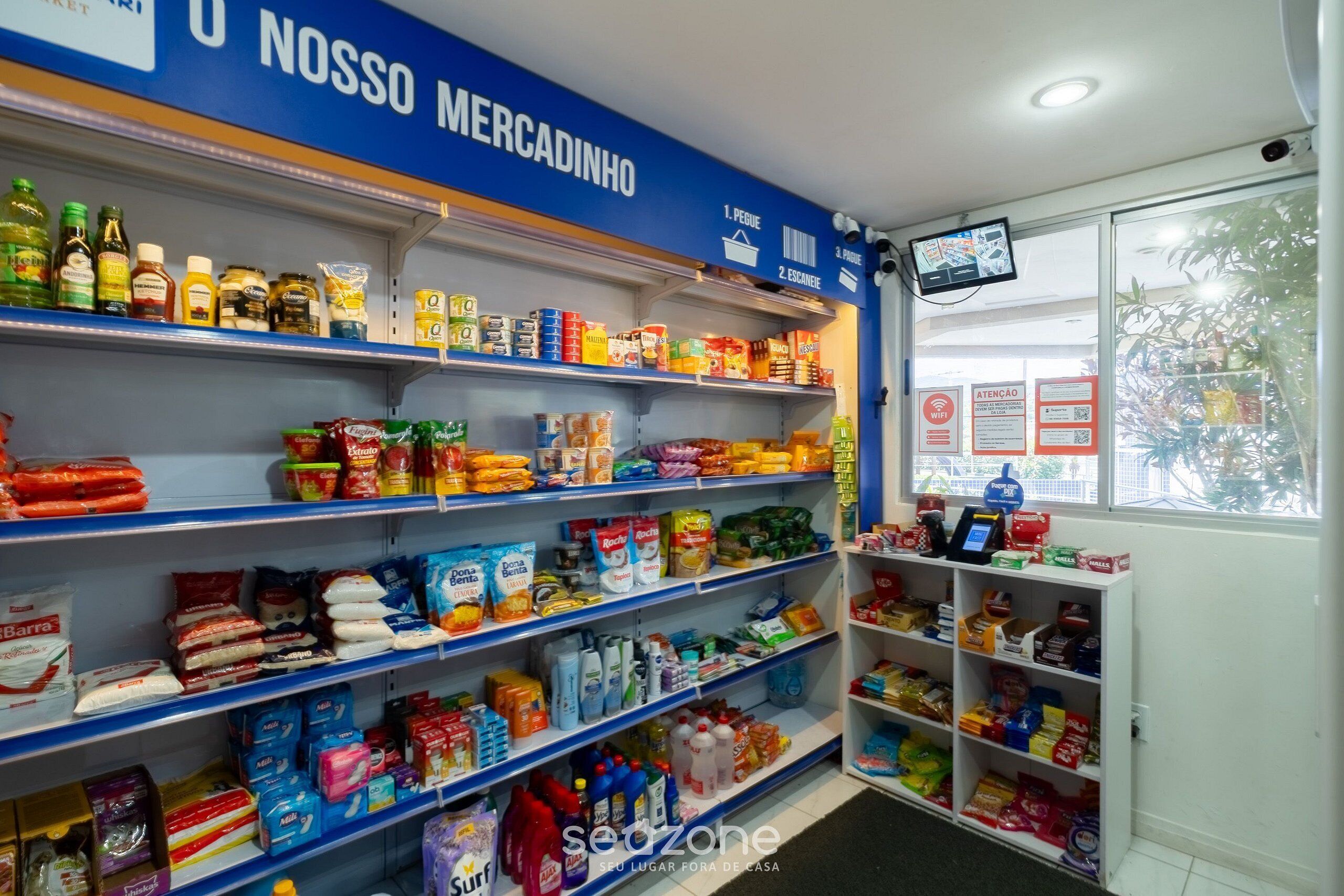 A supermarket interior with shelves stocked with various food items and household goods.