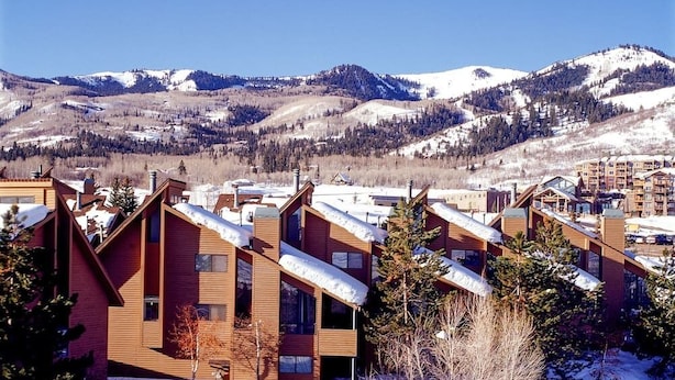 Une ville de montagne enneigée, avec des bâtiments modernes en bois et une vue dégagée sur les montagnes environnantes.