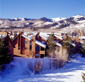 A snow-covered mountain town with modern wooden buildings and a clear view of the surrounding mountains.