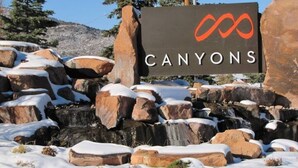 Un paysage enneigé avec une grande formation rocheuse et un panneau indiquant « CANYONS ».