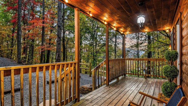 Une terrasse en bois dotée d’une rambarde, d’un escalier et d’un espace véranda avec un luminaire.