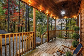 Um deck de madeira com guarda-corpo, escadas e uma varanda com luminária.
