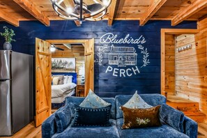 Una habitación acogedora con un sofá azul, paredes de madera y un cartel que dice "Bluebird's Perch".