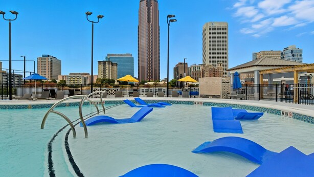 A swimming pool with blue water slides, surrounded by city buildings and street lamps. - High-Rise with Rooftop Pool | Gym | Balcony & Skyline Views (Atlanta)