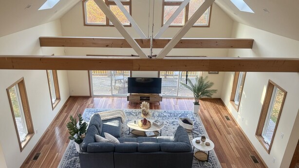 A spacious living room with a high ceiling, skylights, a large TV, and a cozy seating area.