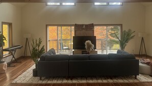 A living room with a large sectional sofa, a flat-screen TV, and a piano.