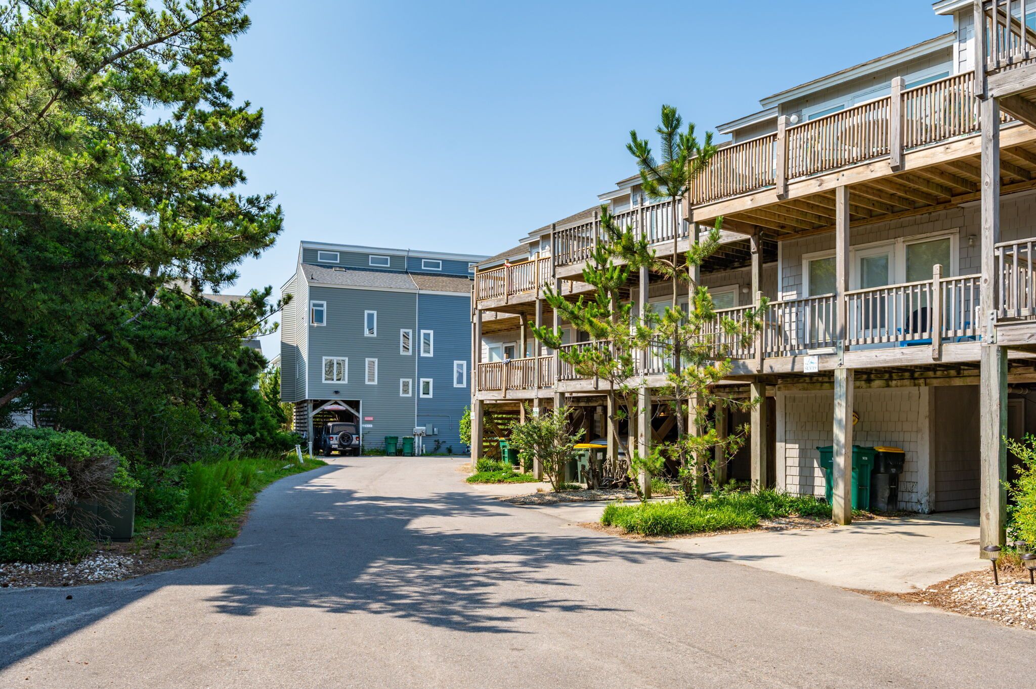 A multi-story building with balconies, a covered parking area, and a clear sky.