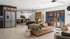 En moderne stue med en beige sofa, et sofabord og et stort abstrakt billede.