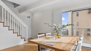Un comedor moderno con una mesa de madera, sillas blancas y un jarrón con plantas.