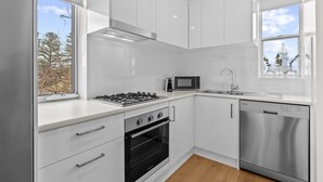 Una cocina moderna con armarios blancos, estufa a gas, microondas y lavavajillas.