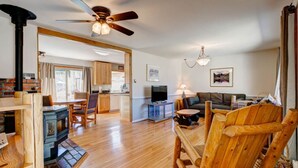 A spacious living area with a wooden floor, a fireplace, a dining table, and a sofa. - Lakeshore Retreat- Estes Park Escape with Mountain & Pond Views (Estes Park)