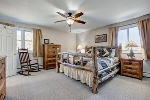 Une chambre à coucher avec un lit en bois, un ventilateur de plafond, une commode, une chaise et une table de chevet avec une lampe.