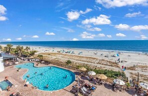 A pool area with a view of the beach and ocean.