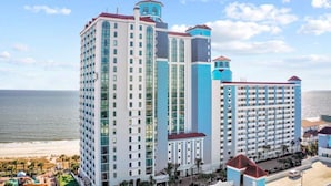 A multi-story hotel with a beach view, featuring a prominent tower and a large building with balconies. - Caribbean 1020 (Myrtle Beach)