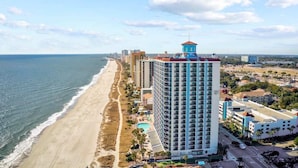 A coastal hotel with a beach view, multiple floors, and a prominent tower. - Caribbean 1020 (Myrtle Beach)