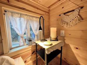 Een gezellige kamer met een raam, een tafel met een kaars en een wanddecoratie.