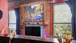 A bar area with a brick wall, a painting above the fireplace, and a window with curtains. - Panther City Pad - Downtown Fort Worth (Fort Worth)