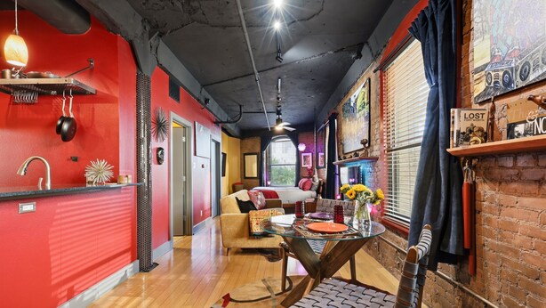 A modern interior with a red wall, a dining area with a glass table, and a brick fireplace. - Panther City Pad - Downtown Fort Worth (Fort Worth)